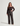 Lola Top Brown — model draagt de kanten top met bruine leren broek, volledige lengte
