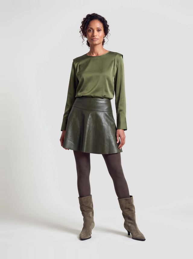 Model draagt de Mary blouse in army groen satijn met leren minirok en suède laarzen, volledig vooraanzicht